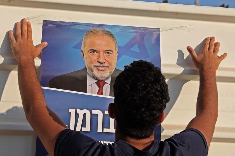 A supporter of Israel's former defence minister Avigdor Lieberman and head of Yisrael Beiteinu party hangs his campaign poster outside a polling station in the West Bank settlement of Nokdim near Bethlehem.  AFP