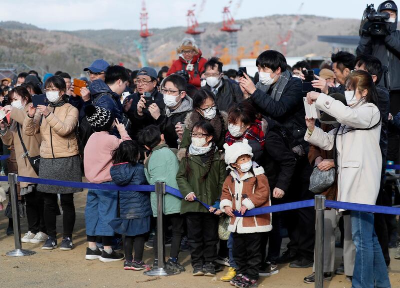 People crowd around the Olympic flame on a cauldron displayed at Ishinomaki Minamihama Tsunami Recovery Memorial Park. EPA