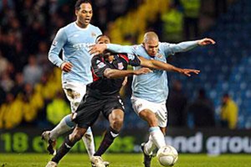 City's Nigel de Jong, right, holds off Stoke's Ricardo Fuller in the teams' first FA Cup tie.