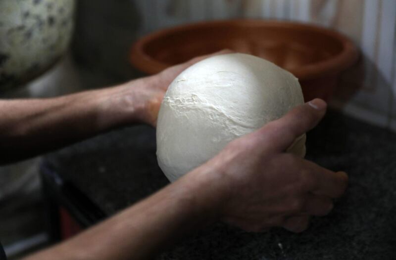 Dough being prepared to make garnished flatbread. AFP