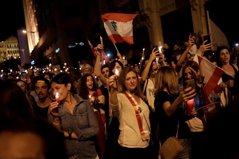 Women carry candles and Lebanese flags as they march during ongoing anti-government protests in Beirut, Lebanon. Reuters