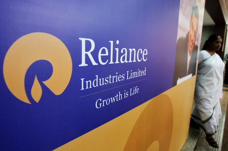 FILE PHOTO: A woman walks past a poster of Reliance Industries installed outside the venue of the company's annual general meeting in Mumbai June 7, 2012.  REUTERS/Vivek Prakash/File Photo