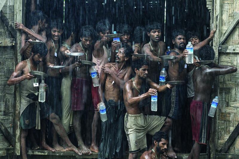 Migrants rescued at sea off the coast of Myanmar’s Rakhine state collect rain water in bottles. Soe Zeya Tun / Reuters / June 4, 2015