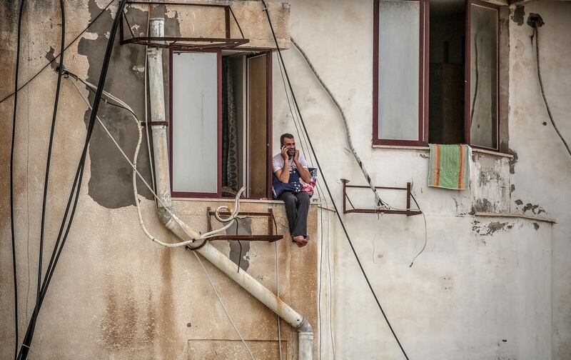 A Palestinian man, who was quarantined, talks on his phone on a hotel window in Gaza City.  EPA