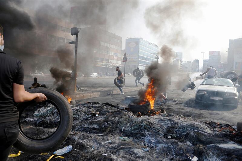 Demonstrators run as they hold tyres during a protest over the deteriorating economic situation, in Dora, Lebanon. Reuters