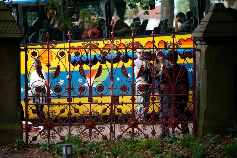 Tourists photograph the replica gates at the original entrance to Strawberry Field.