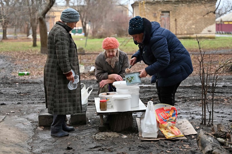 Residents serve up hot food brought by volunteers, in the yard of a residential building in Izyum, Kharkiv region, north-east Ukraine. AFP