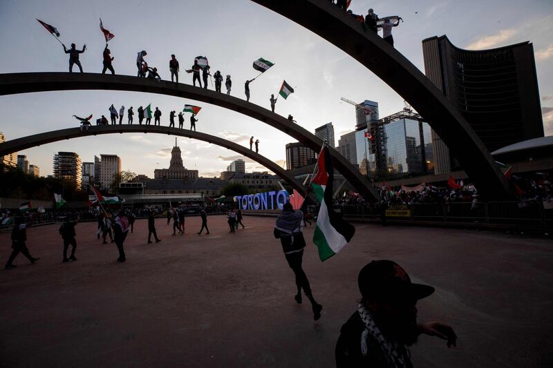 Demonstrators on top of the arches at city hall wave flags as thousands gather in Toronto, Ontario, Canada, to show their support for the people of Palestine. AFP