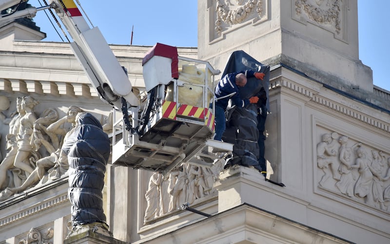 Workers cover a sculpture outside the home of Lviv National Opera to protect it from damage amid fighting in Ukraine. Reuters