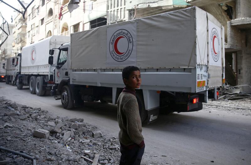 A boy stands as an aid convoy of Syrian Arab Red Crescent drives through the besieged town of Douma, Eastern Ghouta, Damascus, Syria on March 5, 2018. Bassam Khabieh / Reuters