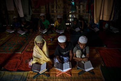 In this photograph taken on August 12, 2018, Saleema Khanam (L), 8, studies inside a makeshift madrassa (Islamic seminary) with other boys in Kutupalong camp, in Ukhia near Cox's Bazar. Islamic seminaries or madrassas, catering to Rohingya children driven from Buddhist-majority Myanmar by a wave of genocidal violence, are springing up in the world's largest refugee camp in Bangladesh since a massive influx of Rohingya Muslims last year. Formal schooling, which suggests a permanent presence, is not allowed in the camps. For many children, the madrassas are the only places to learn. / AFP / CHANDAN KHANNA
