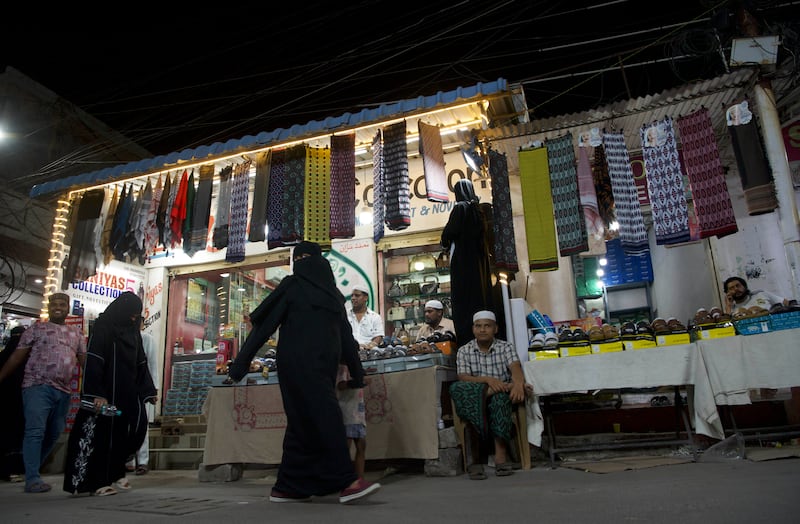 Women walk past shops selling Yemeni futah, a traditional kilt for men