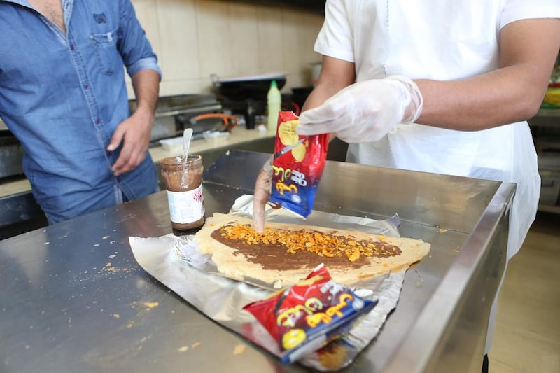Abdulsalam Mohammed, 31, from India, prepares a Nutella regag sandwich with spicy Chips Oman crisps, said by many to be the pinnacle of Nutella sandwiches, at Abu Dhabi’s Al Dhifa cafeteria near Airport Road. Fatima Al Marzooqi / The National