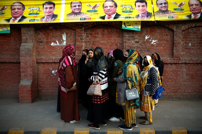 Women wait outside a polling station for voting to begin in Lahore. Reuters