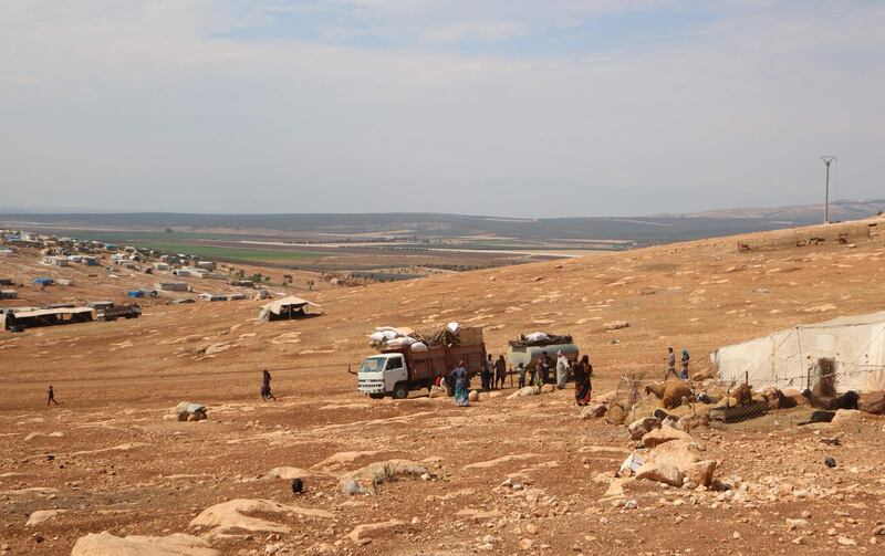 Displaced Syrians who fled from regime raids unload their belongings from a truck in a camp in Kafr Lusin near the border with Turkey in the northern part of Syria's rebel-held Idlib province.  AFP