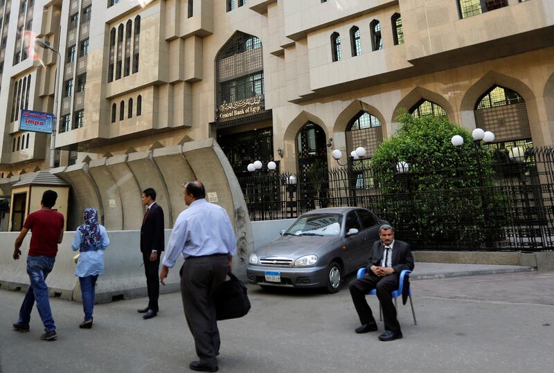 People walk in front of the new headquarters of Central Bank of Egypt, which is secured by cement blocks, in downtown Cairo, Egypt July 25, 2017. Picture taken through a glass window. REUTERS/Amr Abdallah Dalsh