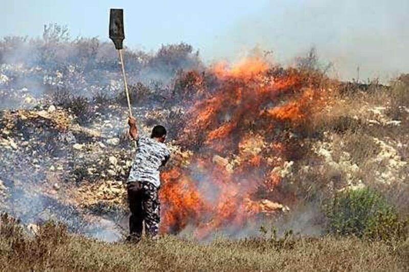 A man tries to douse a fire started by Israeli settlers near the West Bank settlement of Yitzhar.