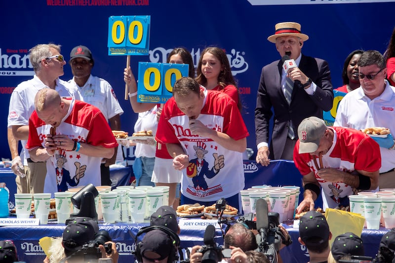 Top male competitive eaters from left, Nick Wehry, Joey Chestnut and Geoffrey Esper eat their first hot dogs and buns. EPA