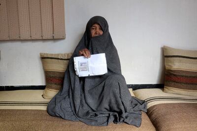 In this photo taken on October 11, 2018. Afghan housewife Fatimah, 55, poses for a picture as she holds her ID card or Tazkira registered to vote in the upcoming parliamentary election, at her House in Mazar-i-Sharif. Bloody violence has forced thousands of polling centres to close and stopped millions of people from registering to vote. But war-torn Afghanistan's long-delayed legislative election will still go ahead on October 20, officials say. Almost nine million people are eligible to vote in the ballot, which is more than three years late and largely funded by the international community.
 / AFP / FARSHAD USYAN
