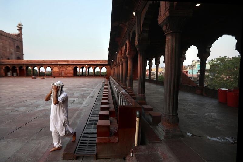 A Muslim wipes his face after performing ablution before prayer at Jama Masjid, New Delhi, India. AP