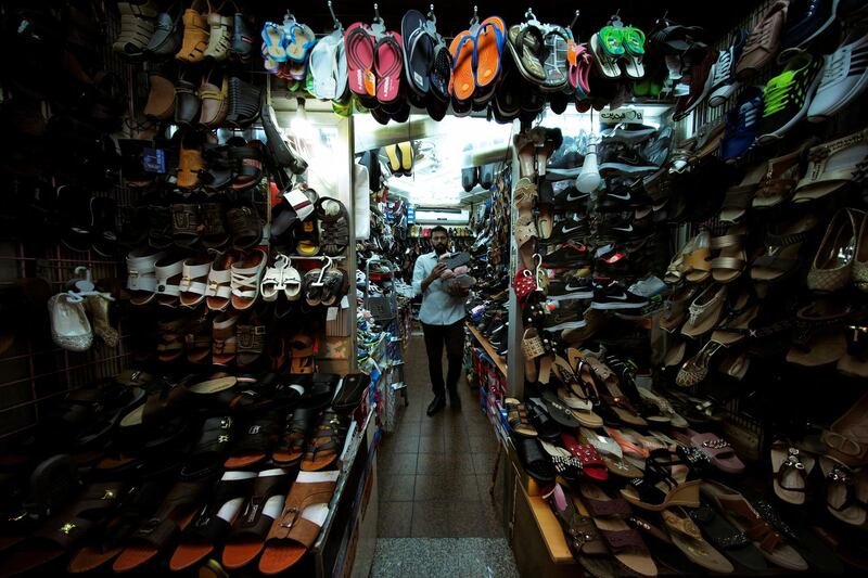 A cobbler brings shoes to be displayed outside as he opens his store in the local souq downtown Manama, Bahrain. Reuters
