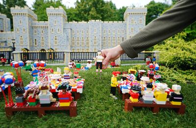 A member of the Legoland Windsor staff places a figure into a display recreating a platinum jubilee picnic scene in front of Windsor Castle. PA