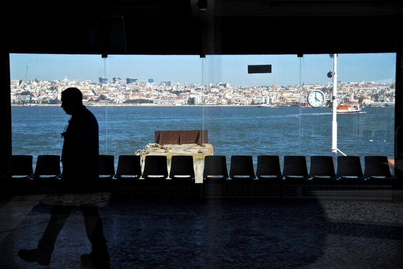 A picture taken on February 25, 2013 shows the silhouette of a man walking by a view of the city of Lisbon, in Cacilhas.  AFP PHOTO /  PATRICIA DE MELO MOREIRA (Photo by PATRICIA DE MELO MOREIRA / AFP)