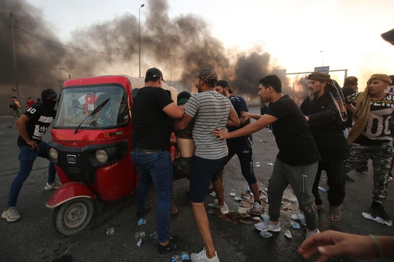 Iraqi protesters assist a wounded comrade in Baghdad. AFP