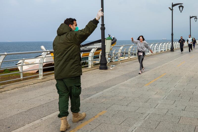 A municipal policeman, left, orders people to evacuate the corniche, or waterfront promenade, along the Mediterranean Sea in Beirut. AP Photo