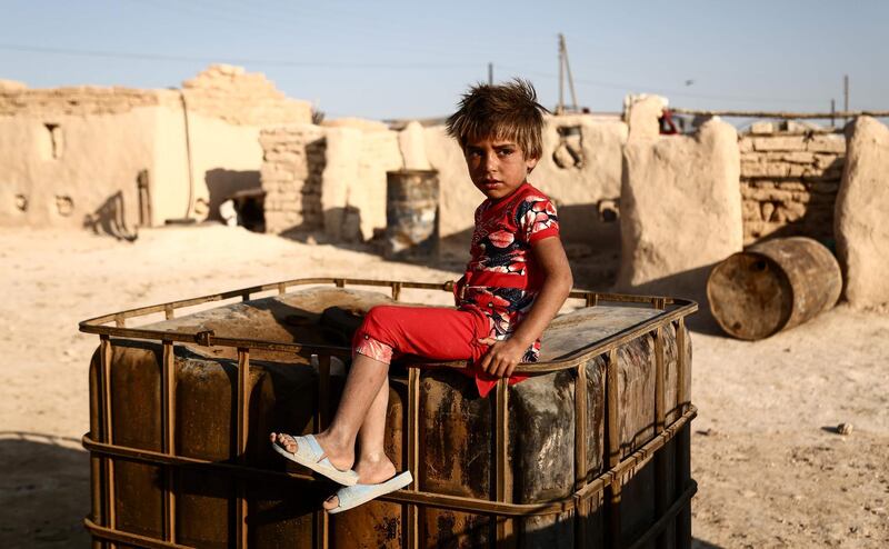 A Syrian child from the northern city of Manbij,  sits outside mud-brick dwellings at Al Qadi camp for the displaced, about 30 kilometres north of Manbij.  Nazeer Al Khatib / AFP Photo