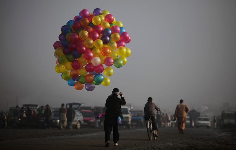 An Afghan youth walks in a street holding his balloons hoping to sell them, in Kabul, Afghanistan, Friday, Nov. 4, 2011. (AP Photo/Muhammed Muheisen) *** Local Caption ***  Afghanistan Daily Life.JPEG-002ae.jpg