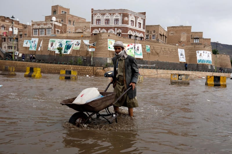 A Yemeni pushes a wheelbarrow through a flooded street following heavy rains in the old quarter of Sana'a, Yemen.  EPA