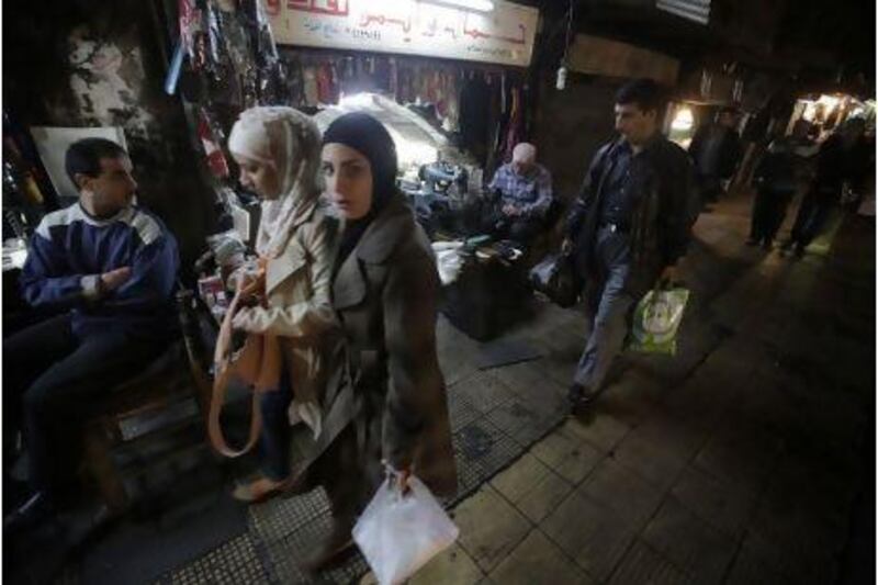 Syrians walk past Damascus shops. In Syria, inflation is said to be running at 40 per cent and families are struggling with food costs.