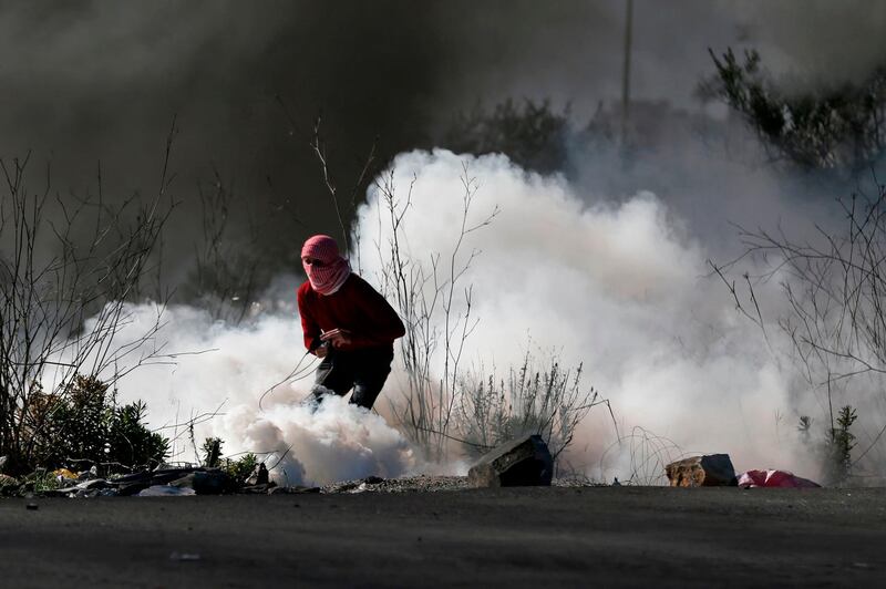 A masked Palestinian protester stands amidst tear gas smoke near Ramallah. Abbas Momani / AFP Photo