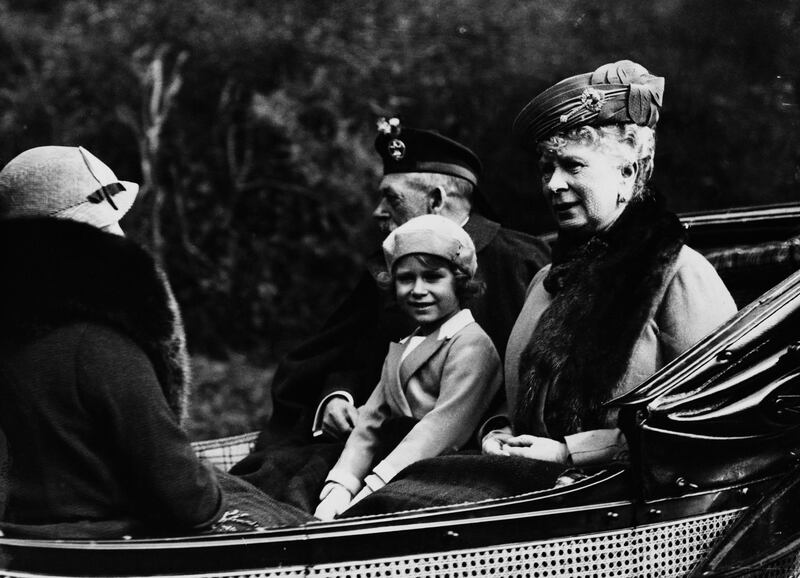 Princess Elizabeth (later Queen Elizabeth II) seated between her grandfather King George V (1865-1936) and grandmother Queen Mary of Teck (1867-1953) as they ride in a carriage back to Balmoral Castle from Crathie Kirk near Braemar in Scotland in August 1935. (Photo by Topical Press Agency/Getty Images)