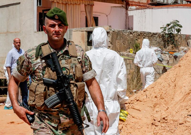 A Lebanese army soldier walks past military intelligence forensic investigators of inspecting the scene where two drones came down in the vicinity of a media centre of the Shiite Hezbollah movement earlier in the day, in the south of the capital Beirut on August 25, 2019. Hezbollah said on August 25 that one of the drones was rigged with explosives and caused damage to its media centre, but denied shooting down any of them. The early morning incident came hours after Israel launched air strikes in neighbouring Syria, but Hezbollah officials could not confirm if the drones deployed in Lebanon were Israeli. Another Hezbollah source told AFP the Iran-backed Shiite militant group -- a major political player in Lebanon with representatives in parliament and the government -- has not determined if the drones were Israeli. / AFP / ANWAR AMRO
