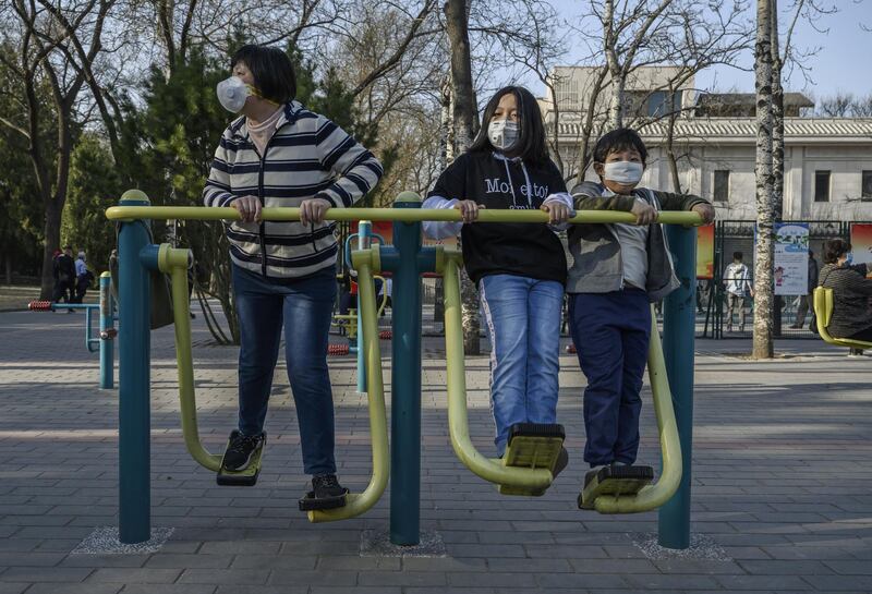 A Chinese  family wear protective masks as they exercise on equipment at Ritan Park in Beijing, China. Getty Images