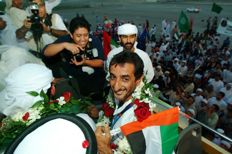 Sheikh Ahmed bin Hashr Al-Maktoum, 40, a member of Dubai's ruling family, is received 26 August 2004 by a crowd of cheerful Emirati citizens upon arriving in Dubai after winning a historic first gold medal during the Athens Olympics in the men's double trap shooting. Al-Maktoum became the first athlete from the UAE to win an Olympic medal of any colour with a superb display of shooting at the Markopoulo Shooting Centre in Athens. AFP PHOTO/Nasser YOUNES (Photo by NASSER YOUNES / AFP)