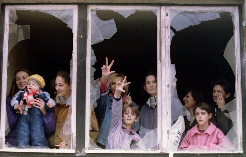 Serbian women and children watch protesters from the shattered windows of an apartment building in Sarajevo in 1995. (Reuters file) 