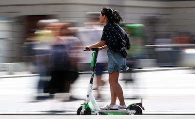 epa07724873 A woman rides on an electric scooter in Berlin, Germany, 18 July 2019. The shared electric scooters have been allowed to circulate in the capital since 15 June 2019. Multiple companies offer this service with a wide range of units parked around the city.  EPA/FELIPE TRUEBA