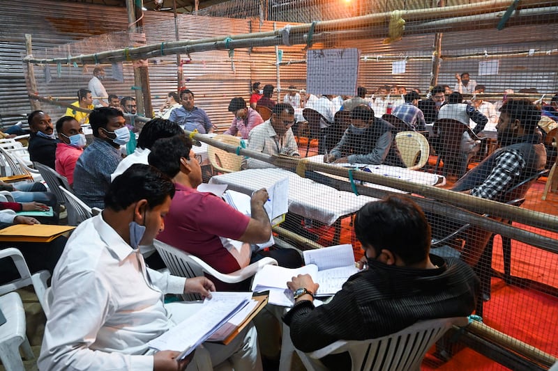 Electoral officials and polling agents wait for electronic voting machines (EVMs) to arrive at a counting centre for the Uttar Pradesh state assembly election votes in Ghaziabad. AFP