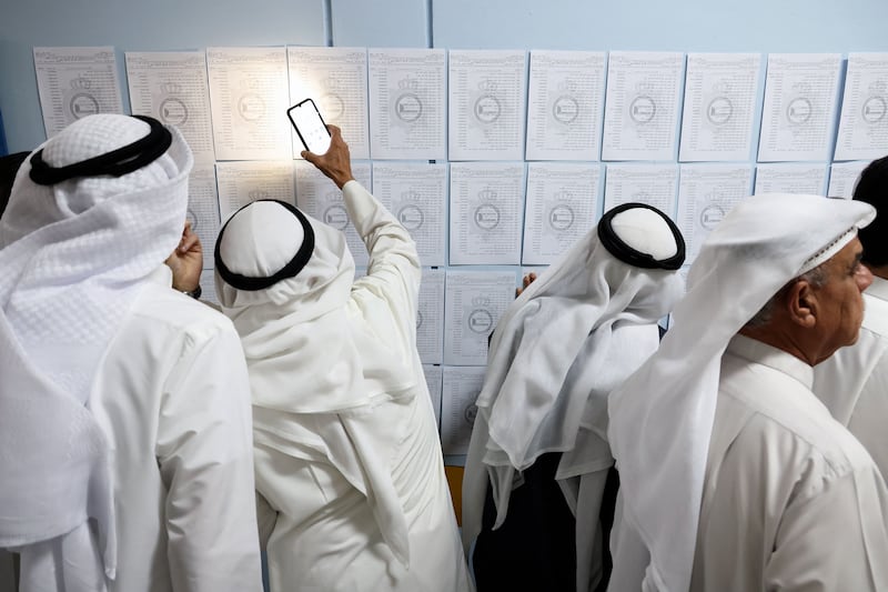 Kuwaiti voters look for their names on electoral lists at a polling station in Kuwait City. AFP