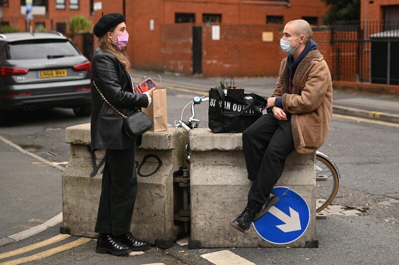 A couple wear face-masks as they chat in the Ancoats district of Manchester. AFP