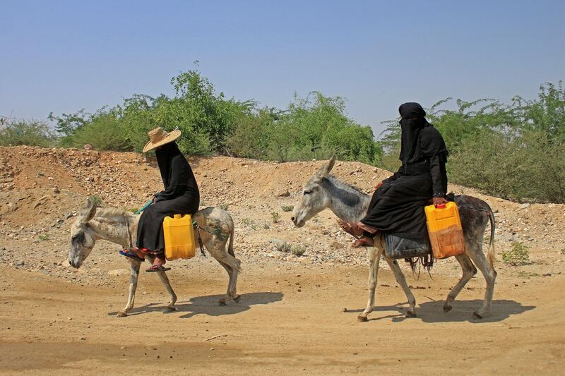 Yemeni women commute on donkeys carrying jerrycans of water at a camp for internally displaced people by conflict in the northern Hajjah province on October 12, 2020. (Photo by ESSA AHMED / AFP)