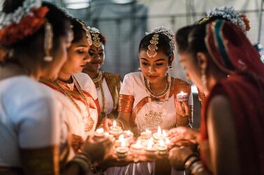 A group of colourful dancers from the Kumari Shiksha Dance Institution light colourful clay lamps in preparation to celebrate Diwali during the two day Diwali (Festival of Lights) Hindu festival celebrations at the old Drive-Inn in Durban, on October 19, 2019. The two-day festival attracts over 100,000 visitors. The festival celebrations include, parading of floats, chariots, singing of devotional songs, dances, games, face painting, food stalls of vegetarian food, clothing, display of toys and jewellery. Young people also get the opportunity to showcase their cultural and spiritual talents. A billion Hindus worlwide will officially celebrate Diwali on 27 October 2019. / AFP / Rajesh JANTILAL