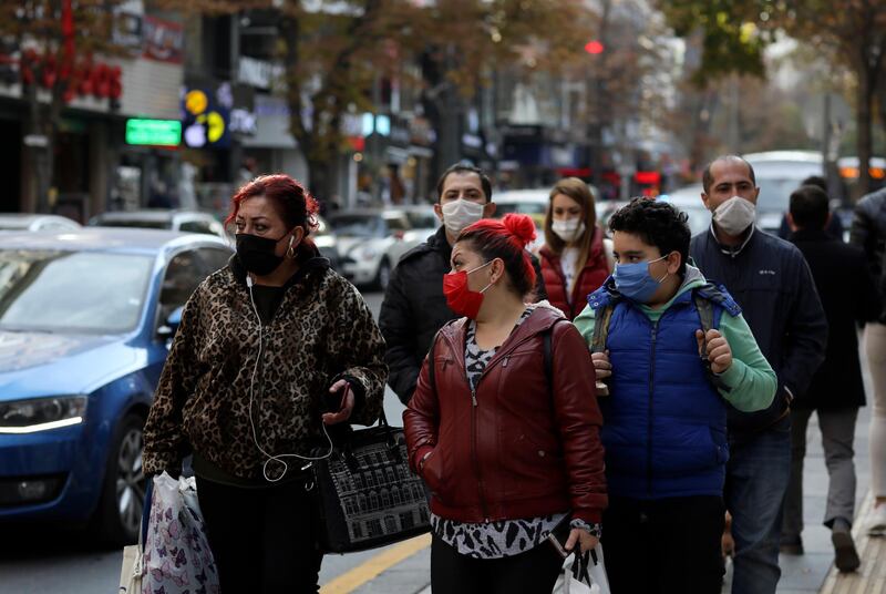 People wearing masks to help protect against the spread of coronavirus, walk, in Ankara, Turkey. Turkey's President Recep Tayyip Erdogan has announced Monday the most widespread lockdown so far amid a surge in COVID-19 infections, extending curfews to weeknights and full lockdowns over weekends. AP