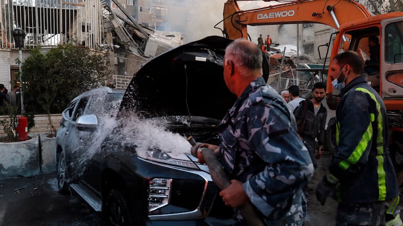 A damaged vehicle is doused following the air strike in Damascus. EPA