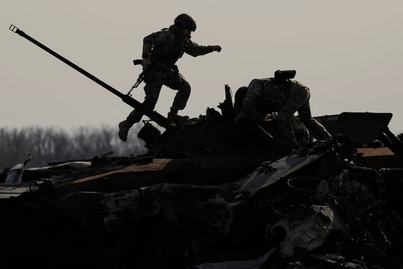 A Ukrainian serviceman walks on a destroyed Russian fighting vehicle in Bucha, Ukraine. AP