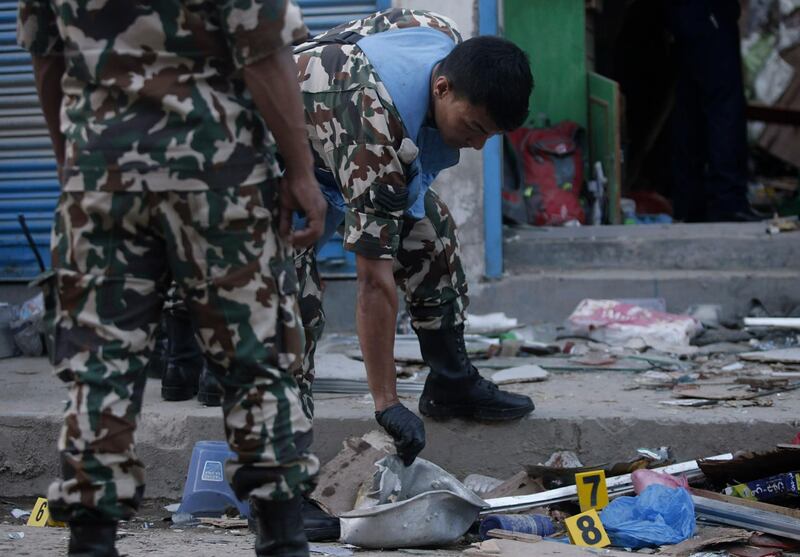 Nepalese army personnel examone the site of an explosion in Kathmandu, Nepal, Sunday, May 26, 2019. Two explosions killed three people and wounded at least five more in different parts of Nepal's capital on Sunday, with police suspecting that an outlawed communist group was responsible. (AP Photo)