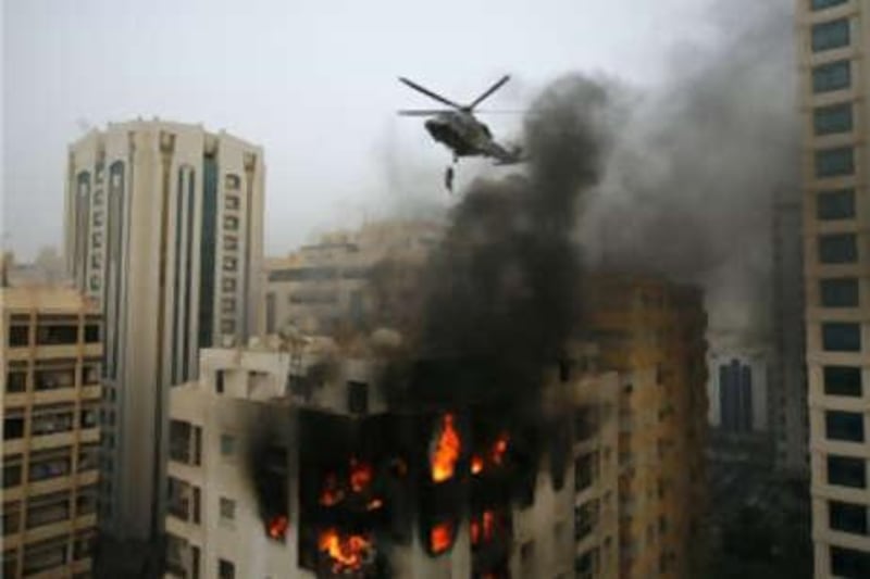 The top floors of a residential apartment building in the Khalidiya area of Abu Dhabi are engulfed in flames, while rescue crews evacuate the remaining residents by helicopter.